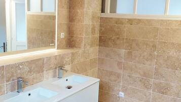 Une salle de bain avec deux lavabos, un grand miroir et une fenêtre en verre dépoli.