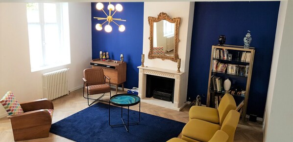 A living room with a fireplace, a bookshelf, and a blue accent wall.