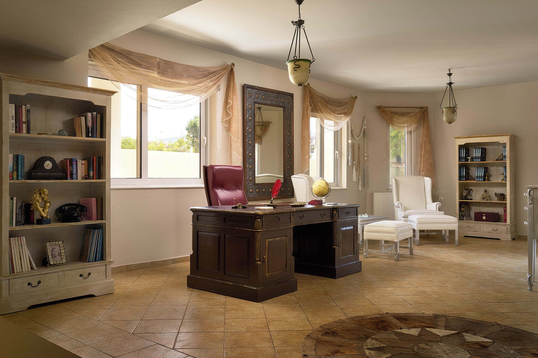 A spacious room with a large desk, a bookshelf, a chair, and a globe.
