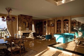 A spacious living room with a large window, a chandelier, and a blue sofa.