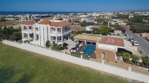 A multi-story building with a pool, surrounded by a fence and greenery. - Marilyn Manor, Exclusive Hideaway with Private Pool & Close to the Beach (Gouves)