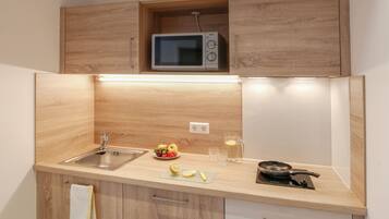 Een koelkast, een magnetron, een kookplaat, kookgerei, borden en bestek