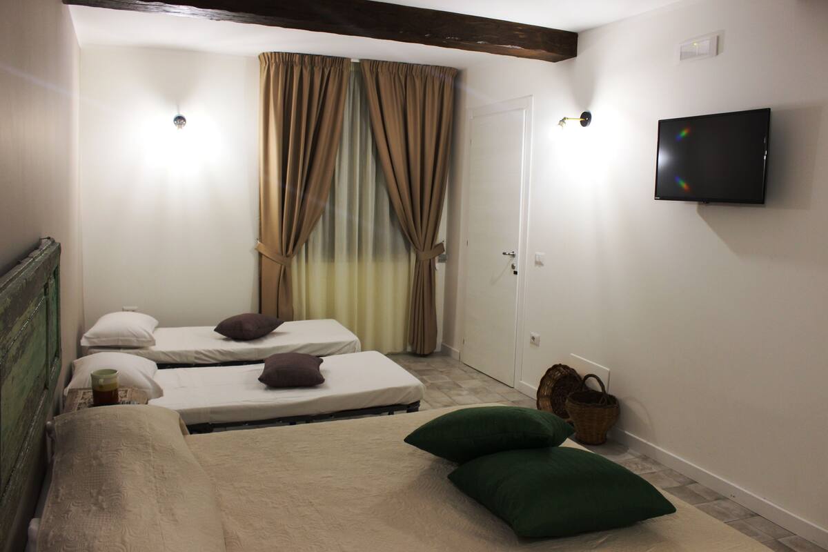 Ein Zimmer mit zwei Einzelbetten, einem an der Wand befestigten Fernseher und einer Tür.