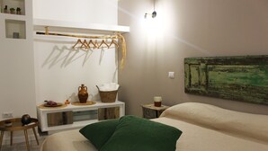 A bedroom with a bed, a bedside table, a hanging rack, and a wall-mounted artwork. - Casa Mazzone BB Experience (Ciro)