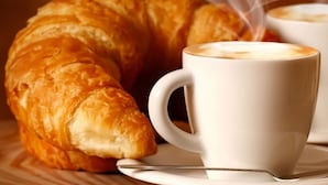 A croissant and a cup of coffee on a table. - Casa Mazzone BB Experience (Ciro)