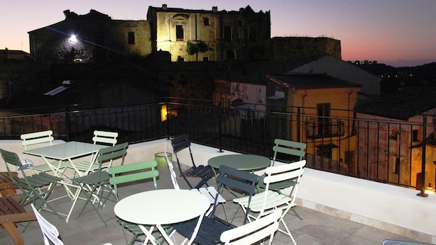 A terrace with outdoor seating and a view of a historic building at dusk. - Casa Mazzone BB Experience (Ciro)