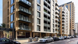 Un edificio residenziale a più piani con balconi, un'area di parcheggio e vista sulla strada.