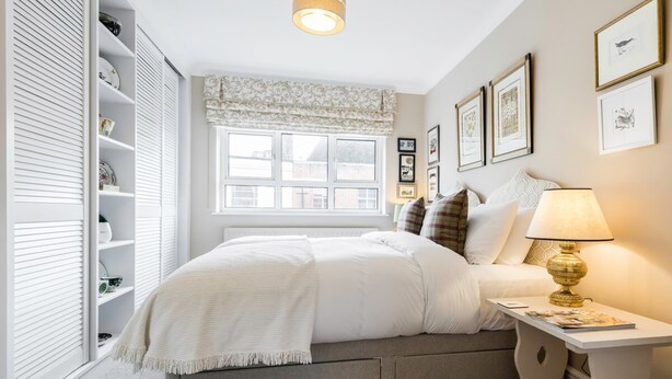 A bedroom with a bed, bedside table, lamp, and wall-mounted pictures. - 3 Bedroom Apartment on Portobello Road in Notting Hill (London)