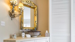 A bathroom with a vanity, a mirror with a floral frame, a towel, and a bottle of Dove soap. - 3 Bedroom Apartment on Portobello Road in Notting Hill (London)
