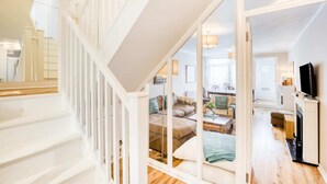 Un vaste espace de vie comprenant un escalier, un ensemble de canapés, un téléviseur et une cheminée.