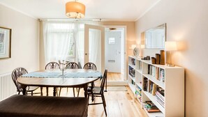 Un coin repas avec une table et des chaises en bois, un lustre et une bibliothèque remplie de livres.