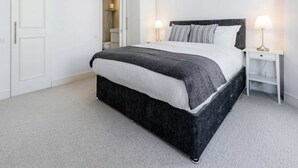 A bedroom with a bed, bedside tables, a wardrobe, and a hanging light fixture. - Elegant Earl's Court 2 bed 2 Bath Near Tube (London)