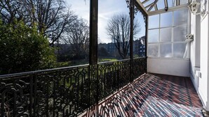 A balcony with ornate black metal railings, a patterned floor, and a view of a park with trees and buildings in the background. - Elegant Earl's Court 2 bed 2 Bath Near Tube (London)