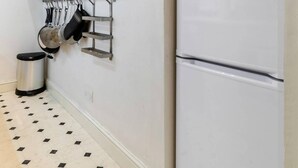 A kitchen with white cabinets, a double-door refrigerator, and a hanging pot rack. - Elegant Earl's Court 2 bed 2 Bath Near Tube (London)