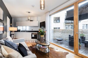 Ein modernes Wohnzimmer mit einer Couch, einem Couchtisch und Blick auf einen Balkon mit Gartenmöbeln.