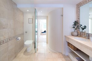 A modern bathroom with a toilet, sink, and large mirror.