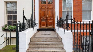 A front view of a house with a wooden double door, a black iron gate, and a white wall. - Lovely 2 Bed near Covent Garden & Tube (London)