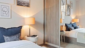A hotel room with a bed, bedside table, lamp, and a mirror. - Lovely 2 Bed near Covent Garden & Tube (London)