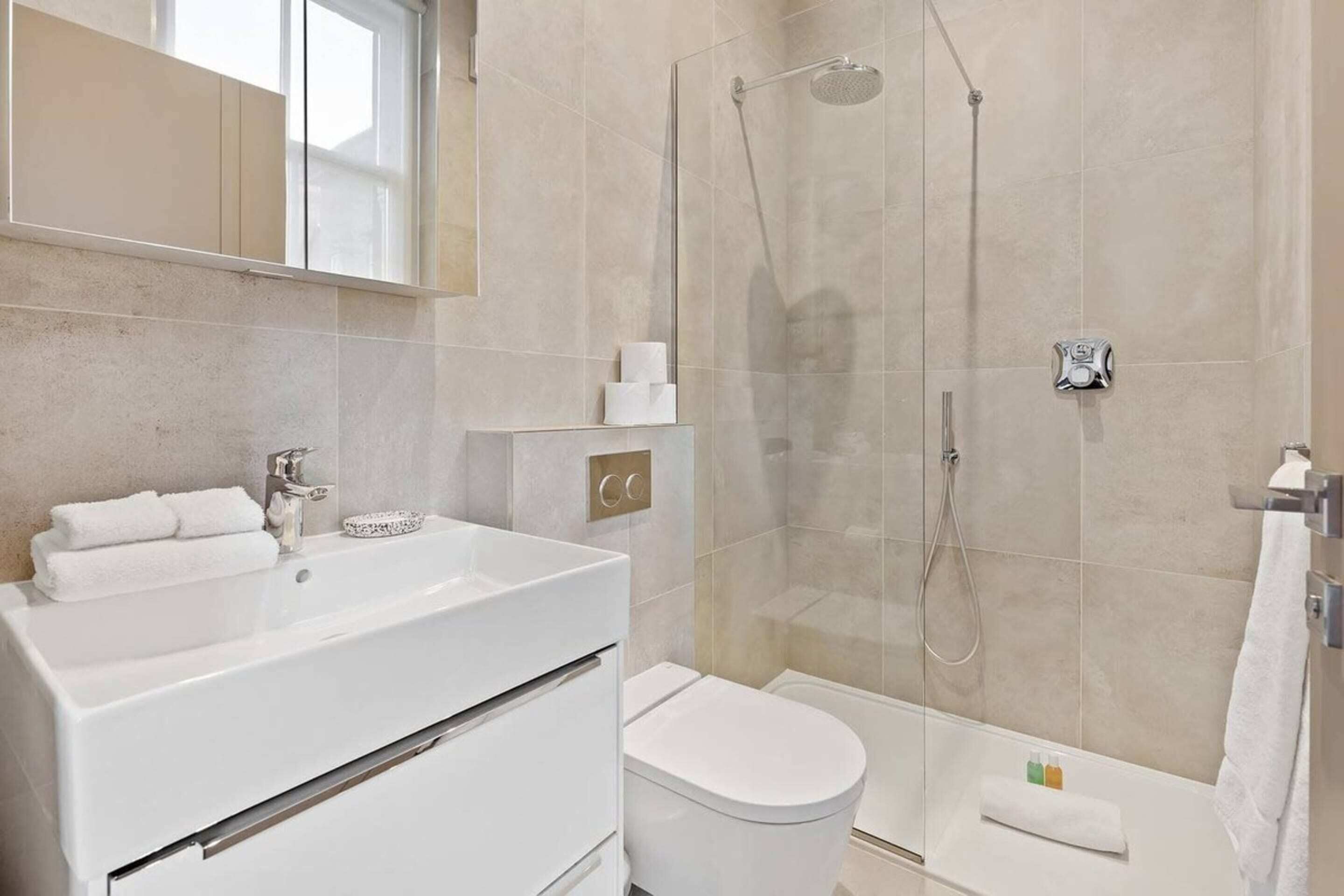 Un bagno moderno con lavandino bianco, wc e doccia con pareti in vetro.