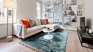 A modern living room with a sectional sofa, a round coffee table, and a large window. - Lovely 2 Bed near Covent Garden & Tube (London)