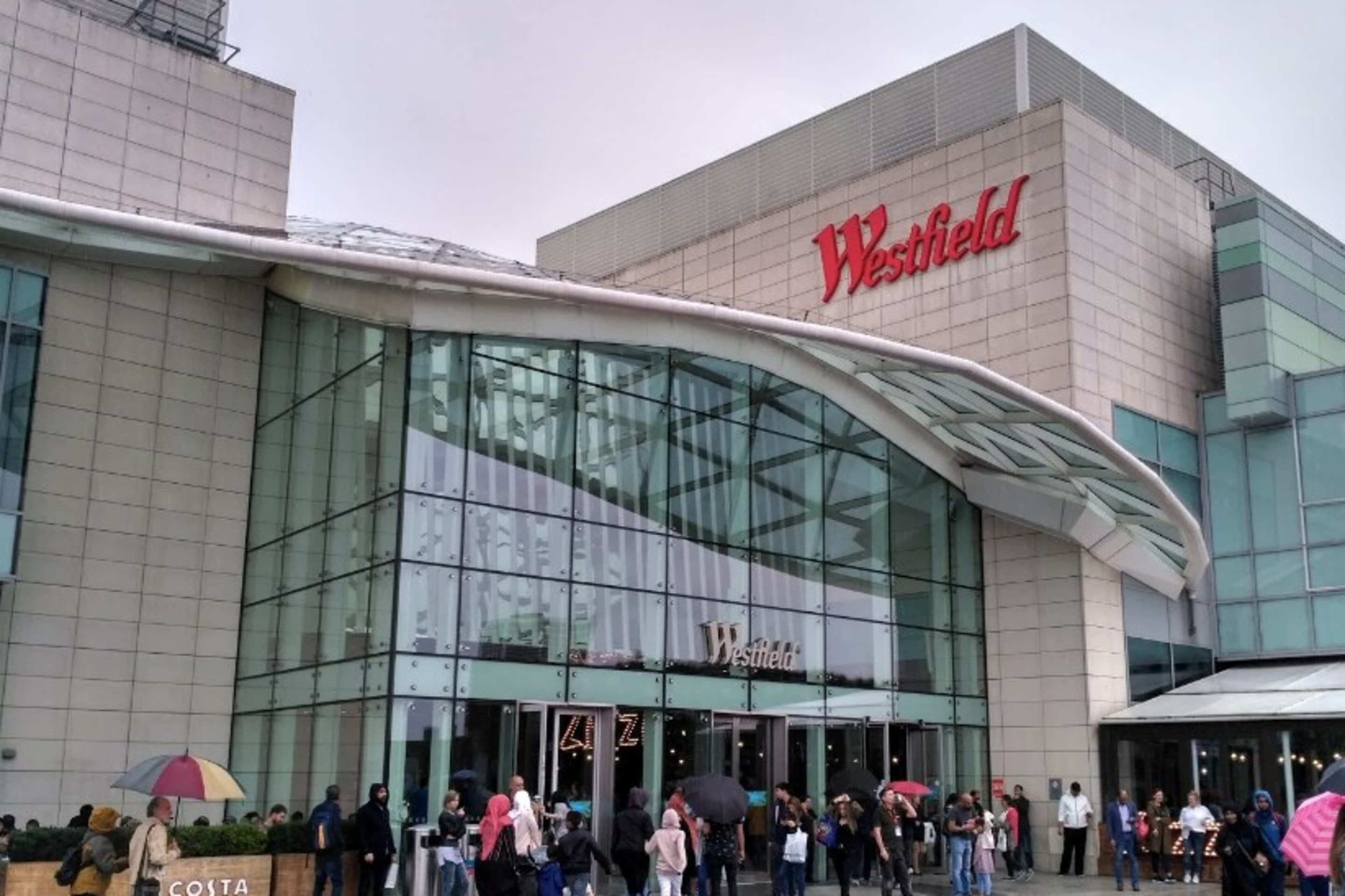A Westfield shopping mall with a modern glass facade and a curved entrance canopy.