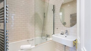 Un baño moderno con ducha de vidrio, lavamanos blanco y espejo.