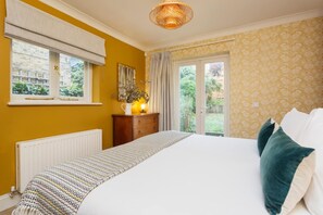 A bedroom with a bed, a window with blinds, a radiator, a wooden dresser, and a curtain. - Stunning 2 Bed Apt W Garden in Clapham (London)