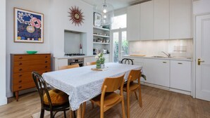 Una cocina moderna con armarios blancos, una mesa de comedor con sillas y un adorno en la pared.