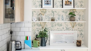 A kitchen with white tiled backsplash, two framed pictures on the wall, a framed poem on the counter, and a small plant. - Trendy 1 Bedroom Apartment in the Heart of London (London)