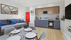 A modern kitchen with grey cabinets, a red refrigerator, and a built-in oven. - Trendy 1 Bedroom Apartment in the Heart of London (London)