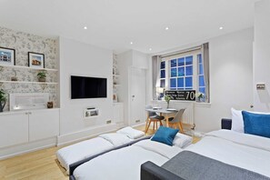 A modern hotel room with two beds, a desk, and a window with a view of a bridge. - Trendy 1 Bedroom Apartment in the Heart of London (London)