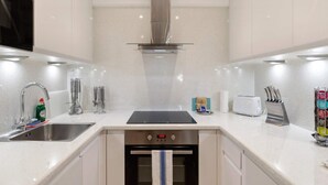A modern kitchen with a stainless steel range hood, a built-in oven, a sink, and a toaster. - Bright 1 Bedroom House near Edgware Road (London)