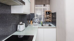 A compact kitchen with a toaster, a sink, and a window with a view. - Modern 2 Bedroom Apartment in Marble Arch (London)