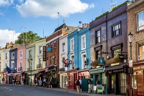 A row of colorful buildings with various shops and signs, including a highland store and antiques arcade. - Remarkable 5 Bed, 4,5 Bath W Garden Near Nottinghill (London)