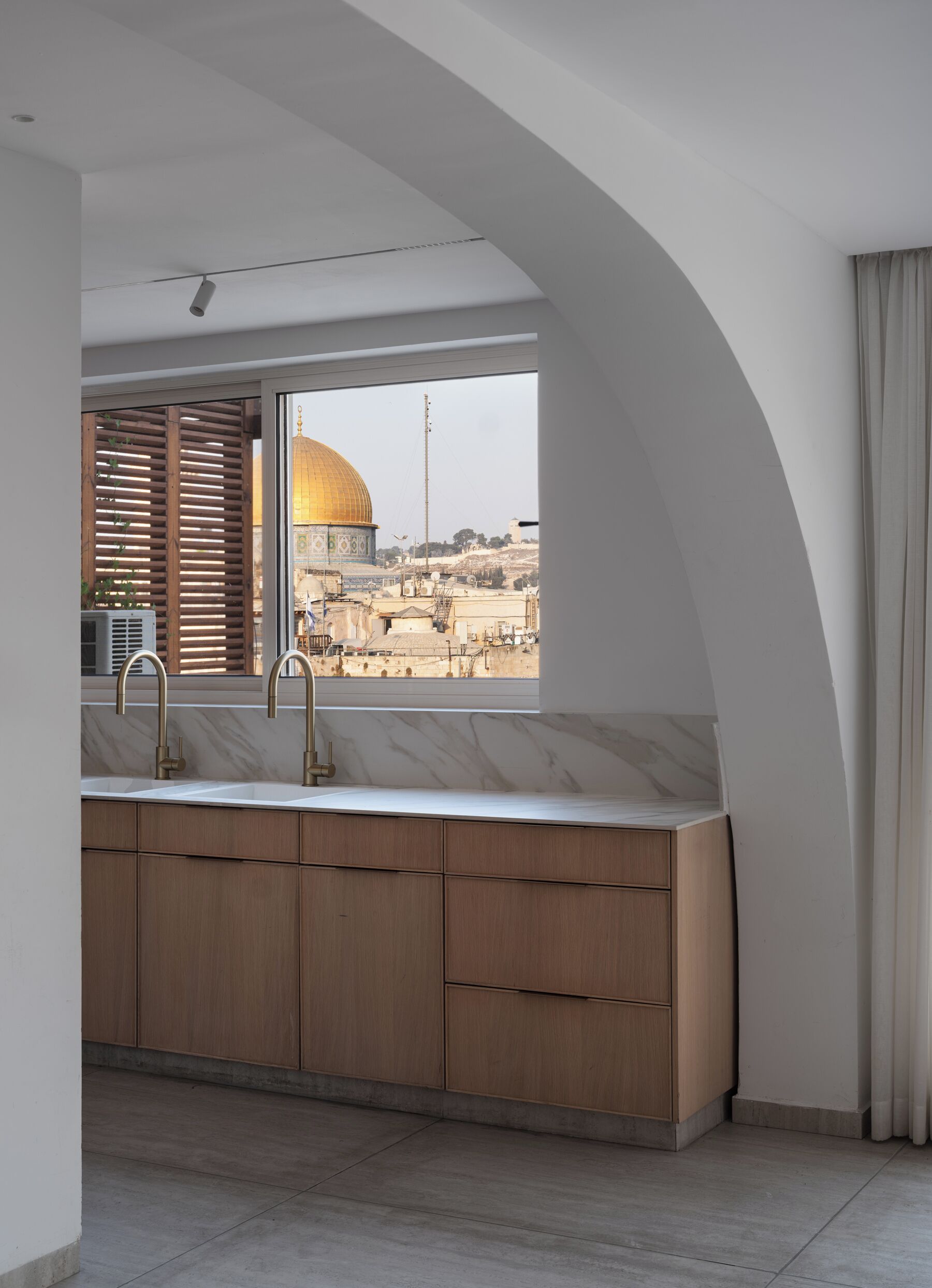 A modern kitchen with a large window, wooden cabinets, and a view of a dome structure.