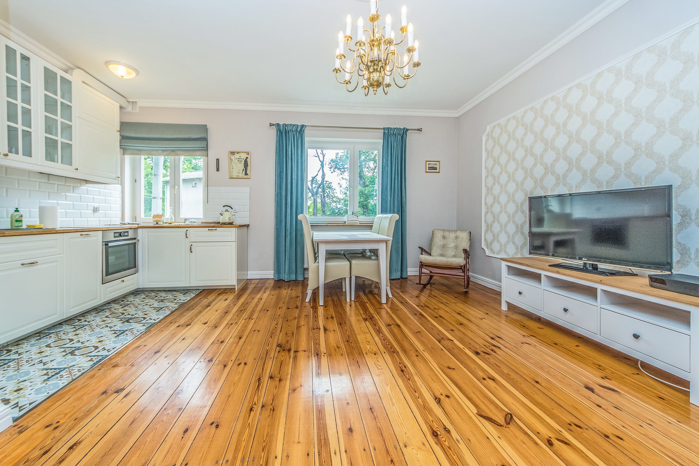 Une cuisine spacieuse avec un plancher en bois, une table à manger et un meuble pour la télévision.