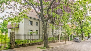 A residential street with a paved sidewalk, a metal fence, and a parked car. - Victus Apartament Dębowa (Sopot)