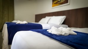 Two hotel beds with white linens and blue bedspreads, each with a white towel on the bed. - Pousada Paraíso das Palmeiras (Paripueira)