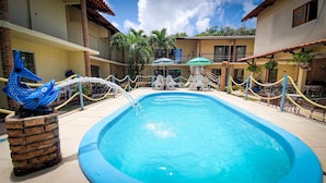 A swimming pool with a decorative fish sculpture, surrounded by a fenced area with chairs and umbrellas. - Pousada Paraíso das Palmeiras (Paripueira)