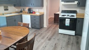 Una cucina compatta con mobili grigi, un tavolo da pranzo in legno e un piano cottura bianco.
