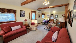 A cozy living room with red sofas, a patterned armchair, and a dining area with wooden furniture. - Wonderful Quiet neighborhood retreat in the Village of Watkins Glen (Watkins Glen)