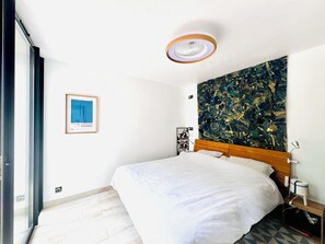 Quarto com cama, ventilador de teto, tapeçaria e um quadro na parede.