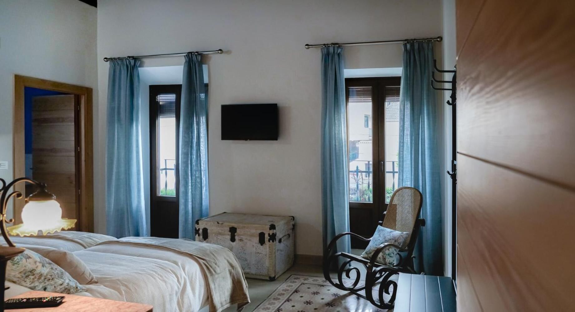 A bedroom with a bed, a suitcase, a chair, and a television on the wall.