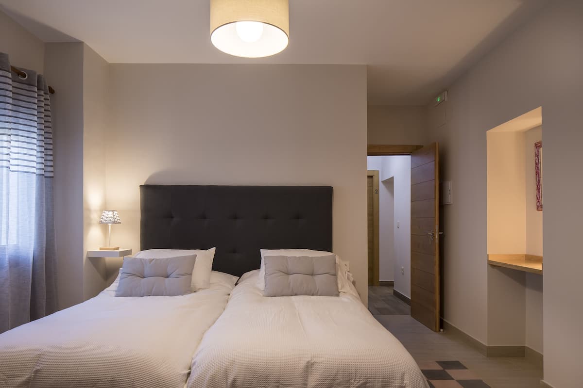Un lit double avec une tête de lit sombre, dans une chambre d’hôtel.