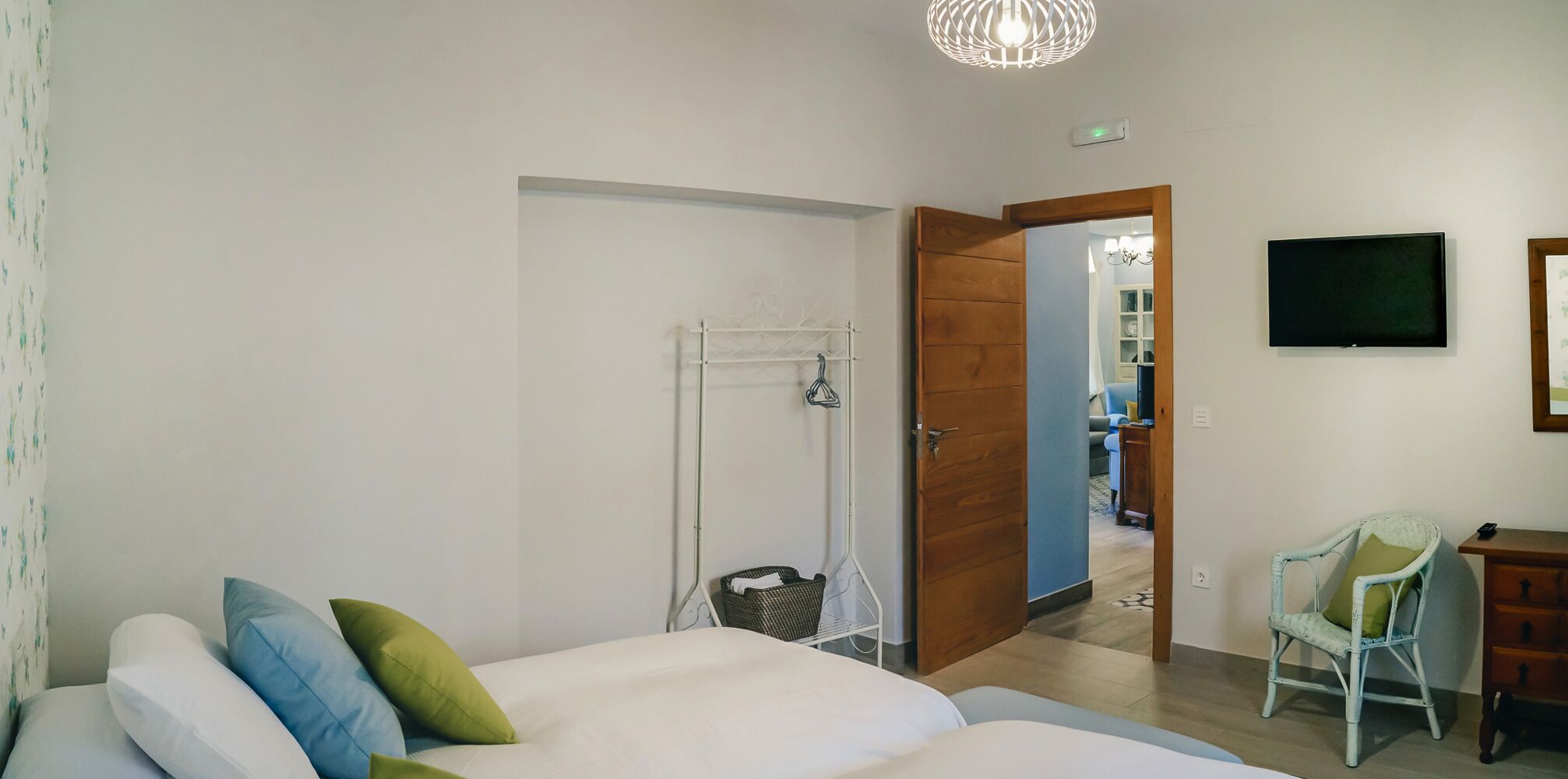 Un dormitorio con cama, una silla, un televisor y un armario.