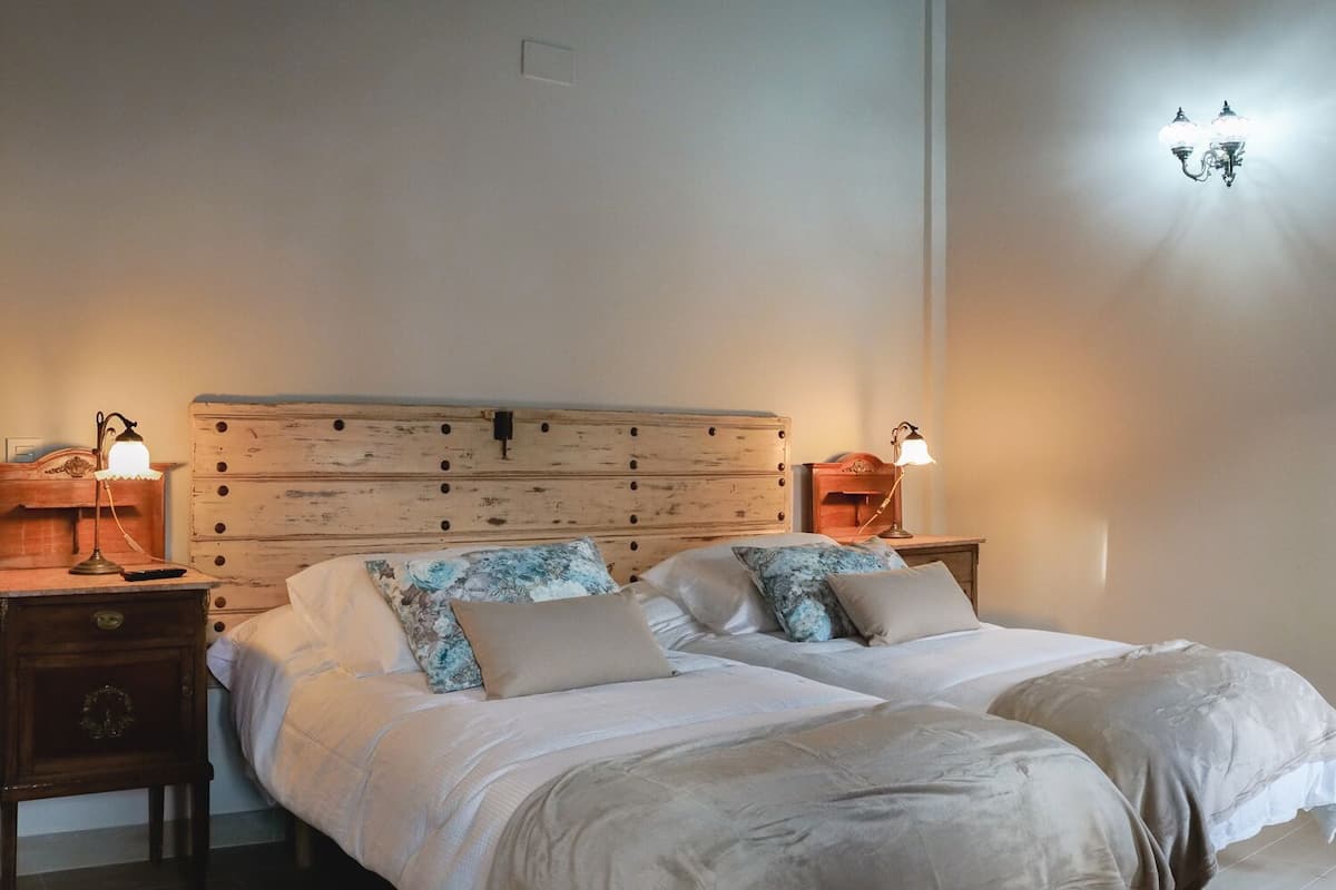 Une chambre avec deux lits, une tête de lit en bois, des lampes de chevet et une vue sur un balcon.