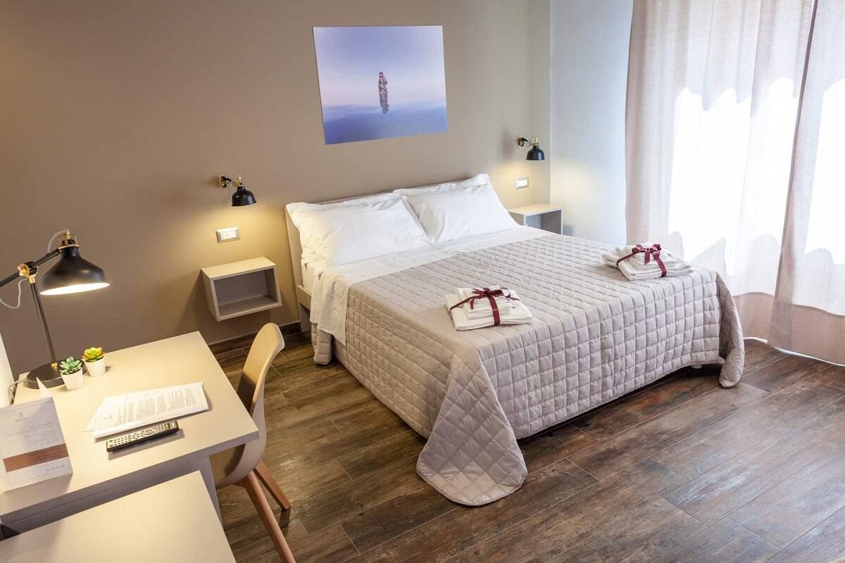 Ein ordentlich eingerichtetes Hotelzimmer mit Bett, Nachttischen, Schreibtisch und Stuhl.