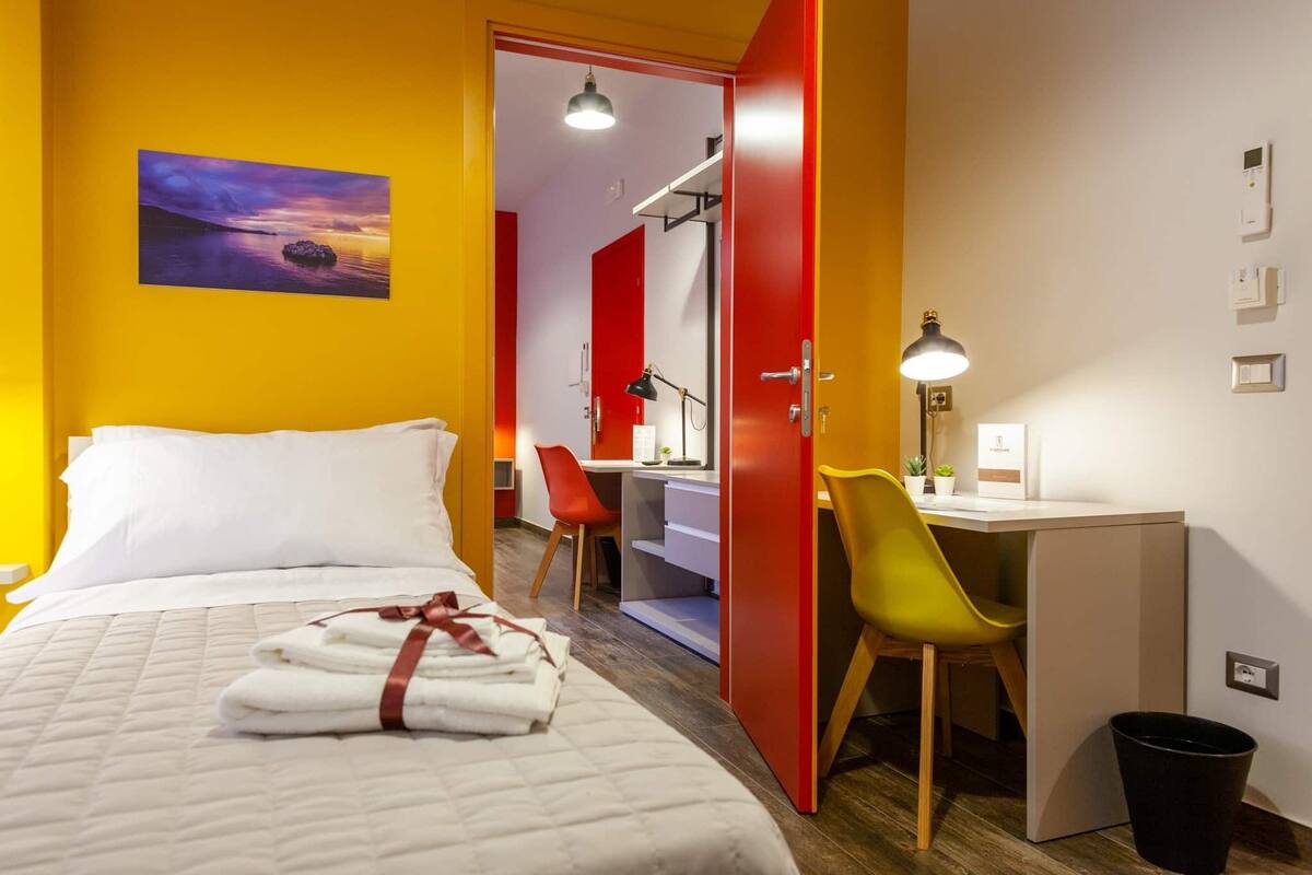 Ein Hotelzimmer mit Bett, Schreibtisch, Stuhl und Schreibtischlampe.