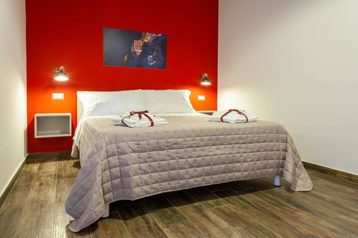 Ein Hotelzimmer mit einem Bett, roten Wänden und einem Gemälde über dem Bett.