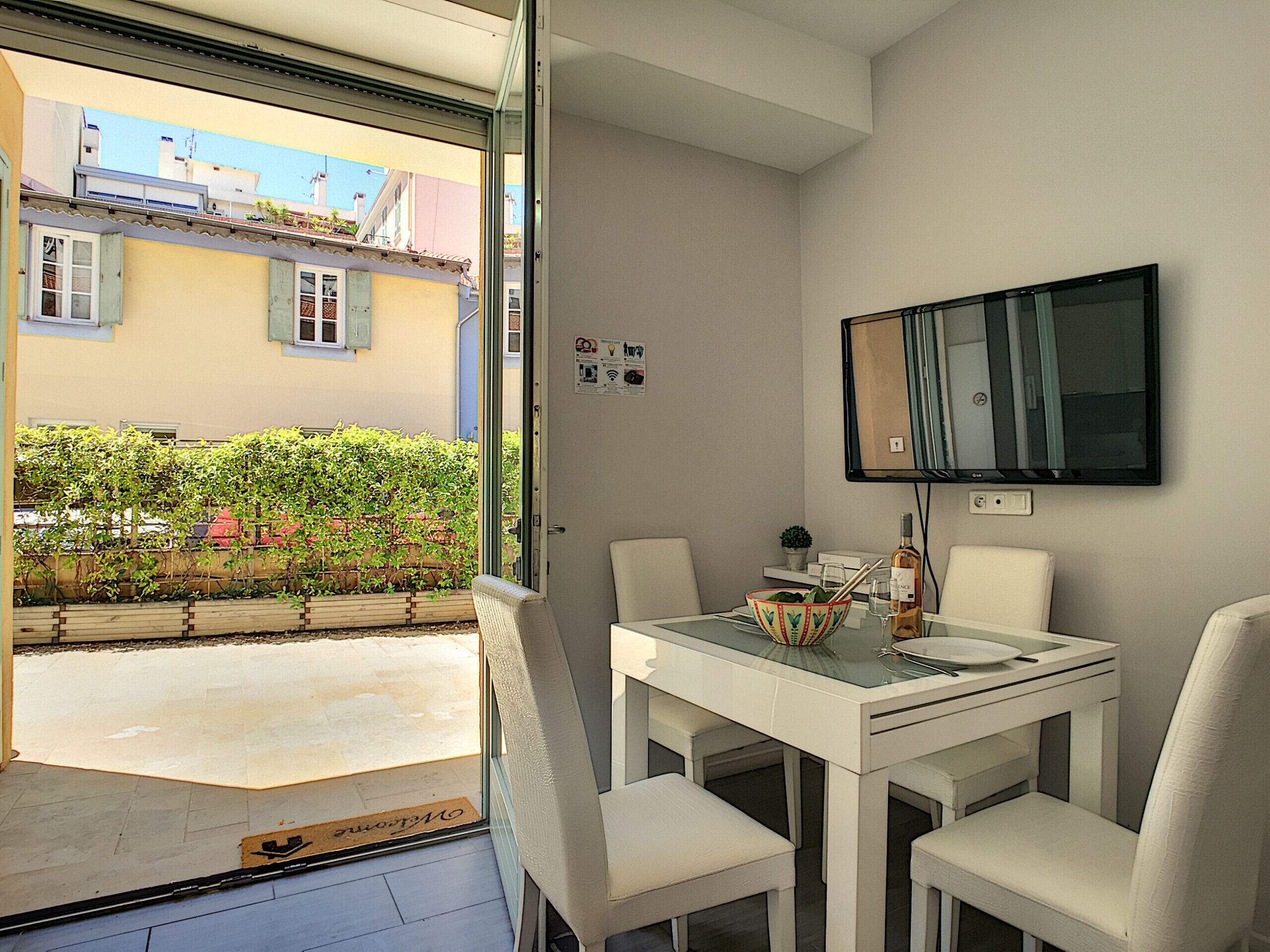 A dining area with a table, chairs, a TV, and a view of the outside.